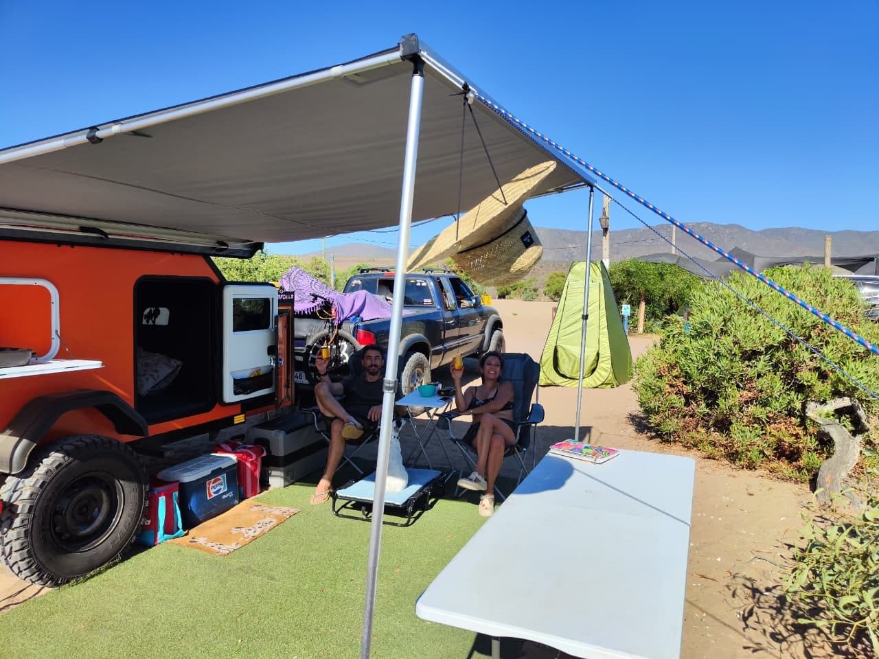 Mini Camper en camping con toldo desplegado, mesa y sillas plegables