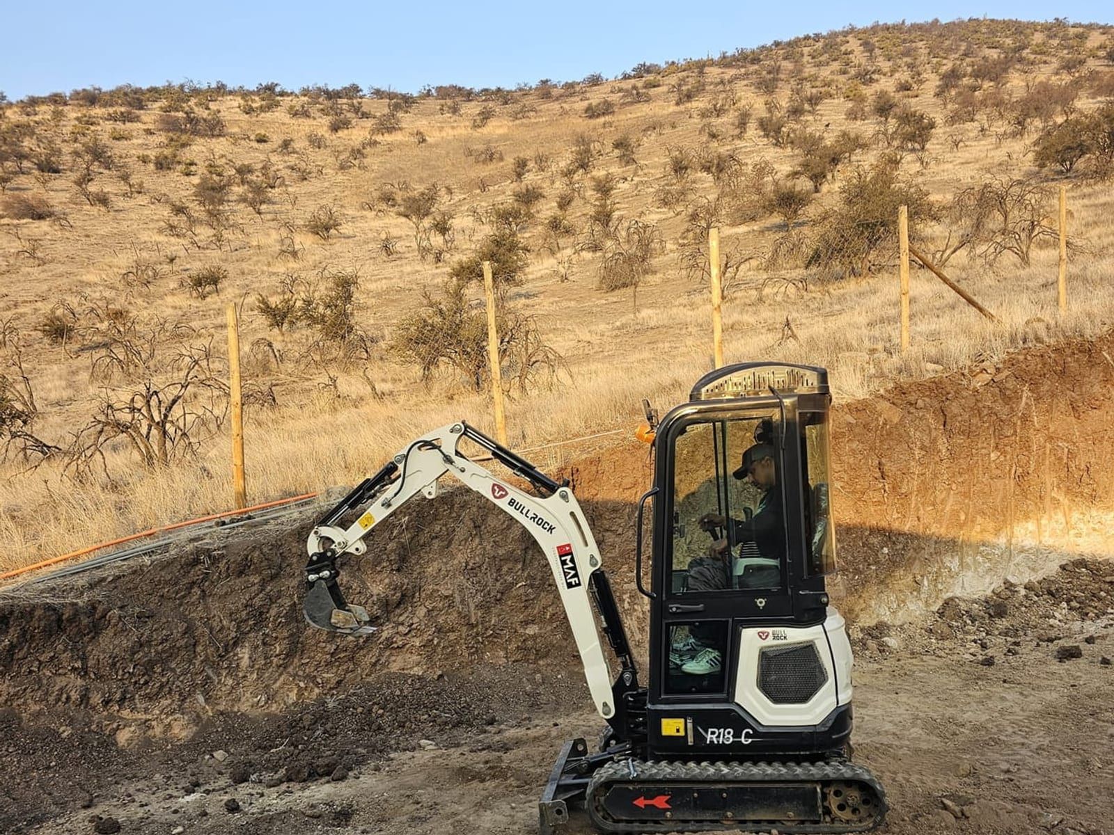 Miniexcavadora 1.8 ton Bullrock BR18-C arrendada por Servicios DLV excavando en faena de Santiago con vista al cerro