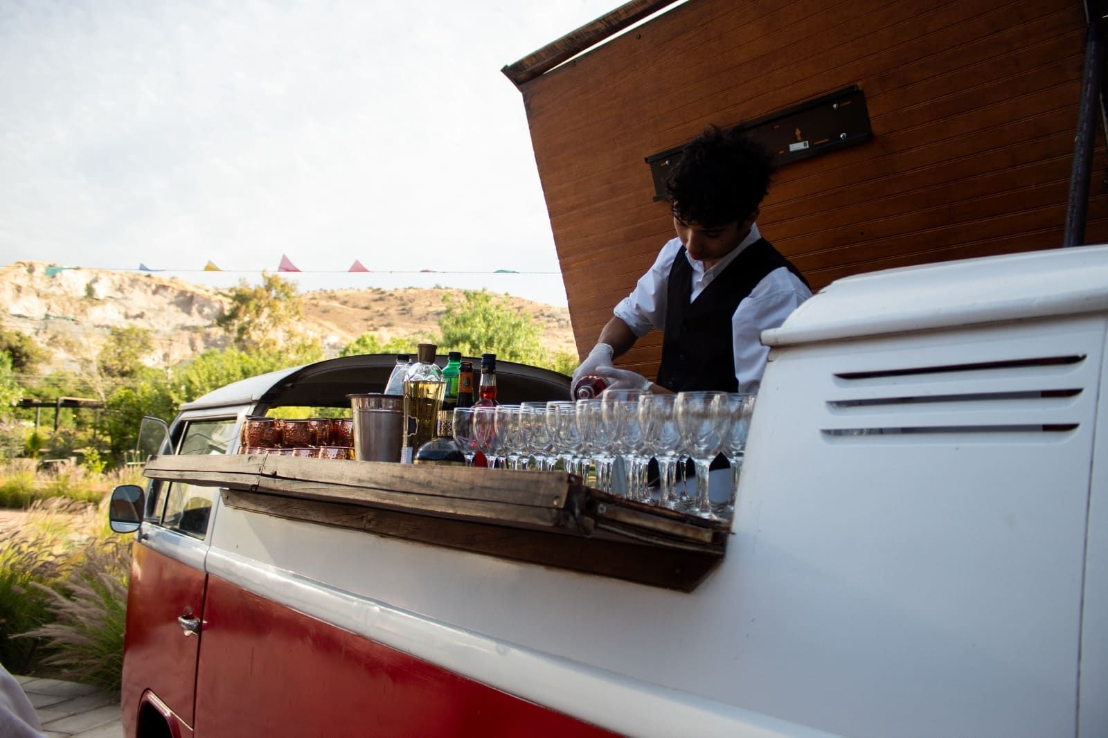 Bartender preparando cócteles en la barra de madera integrada de la Kombi VW DLV durante evento privado
