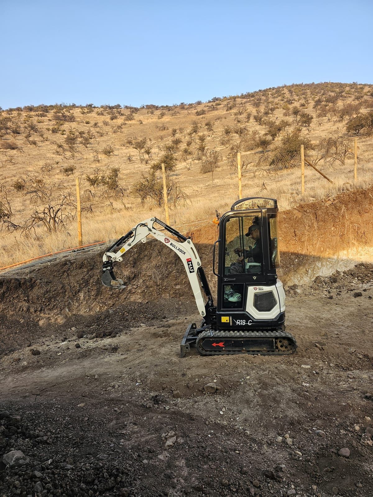 Miniexcavadora 1.8 ton Bullrock excavando en cerro seco con vista panorámica