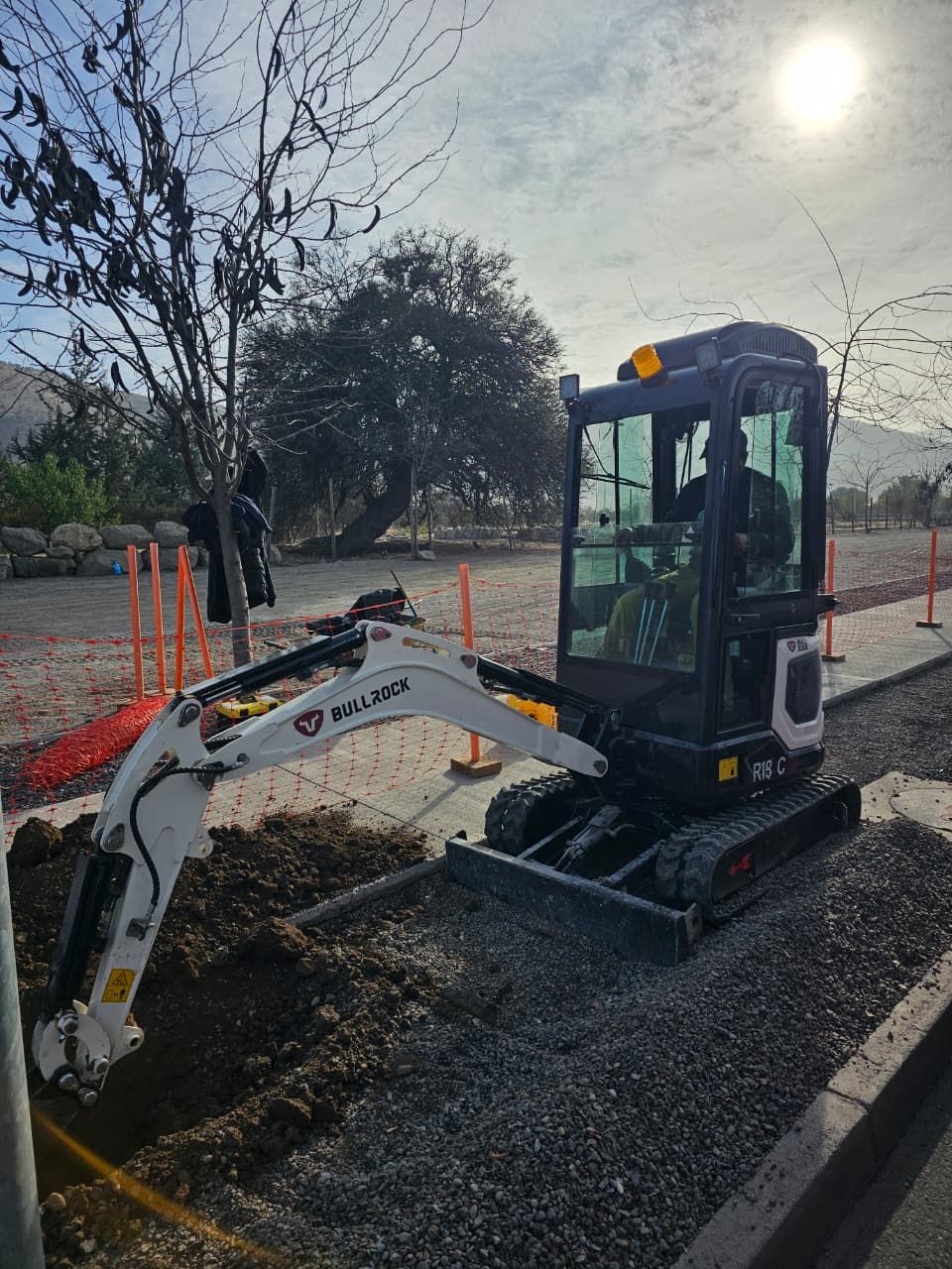 Bullrock BR18-C excavando zanja junto a sendero en área verde